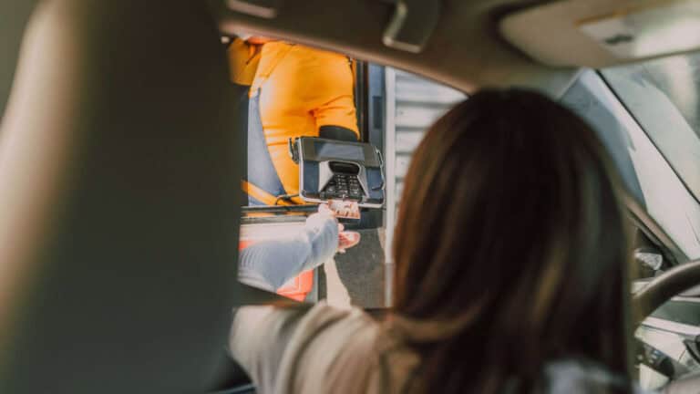 Image of a woman inserting a credit card at a drive-thru to illustrate the topic of loss prevention in retail stores.