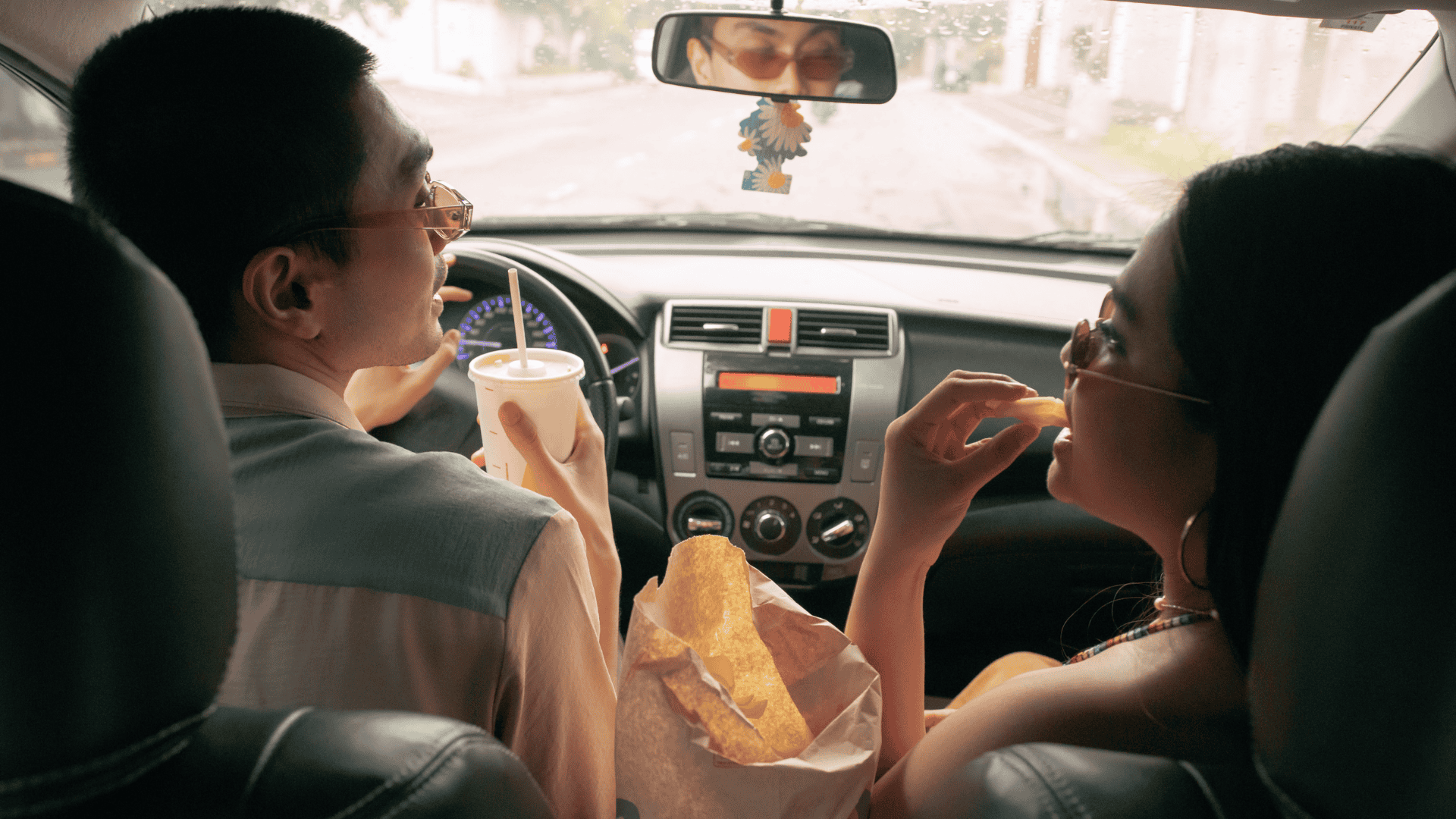 Young man and woman couple in a car as an example of customer behavior in QSR.