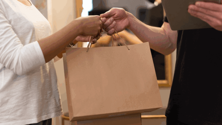 Man handing a paper bag to a customer as an example of a retail customer experience strategy.