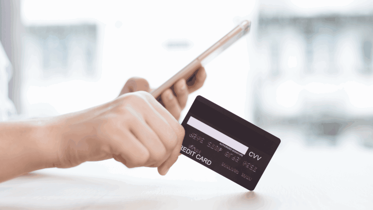Image of a person's hands holding a cell phone in one and a credit card in the other as an example of QSR Loss Prevention.