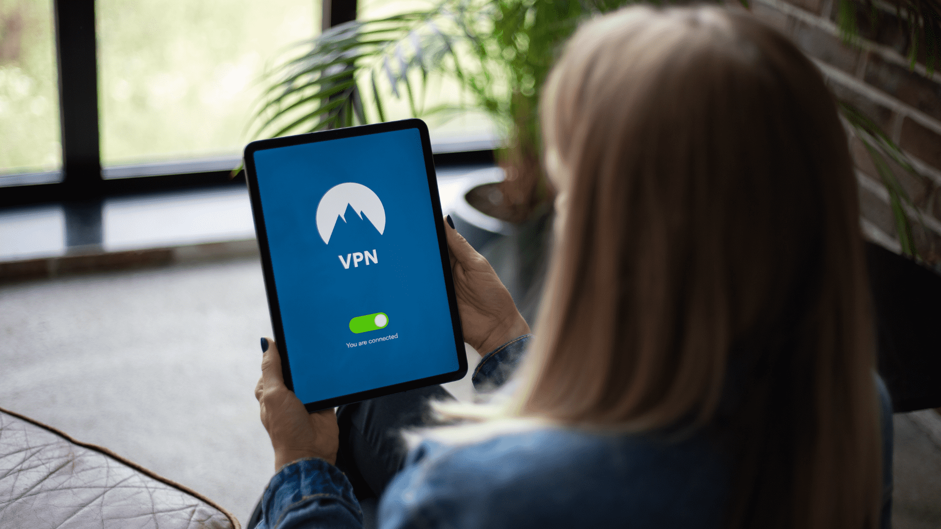 Woman with a tablet showing the logo of NordVPN, a Virtual Private Network (VPN).