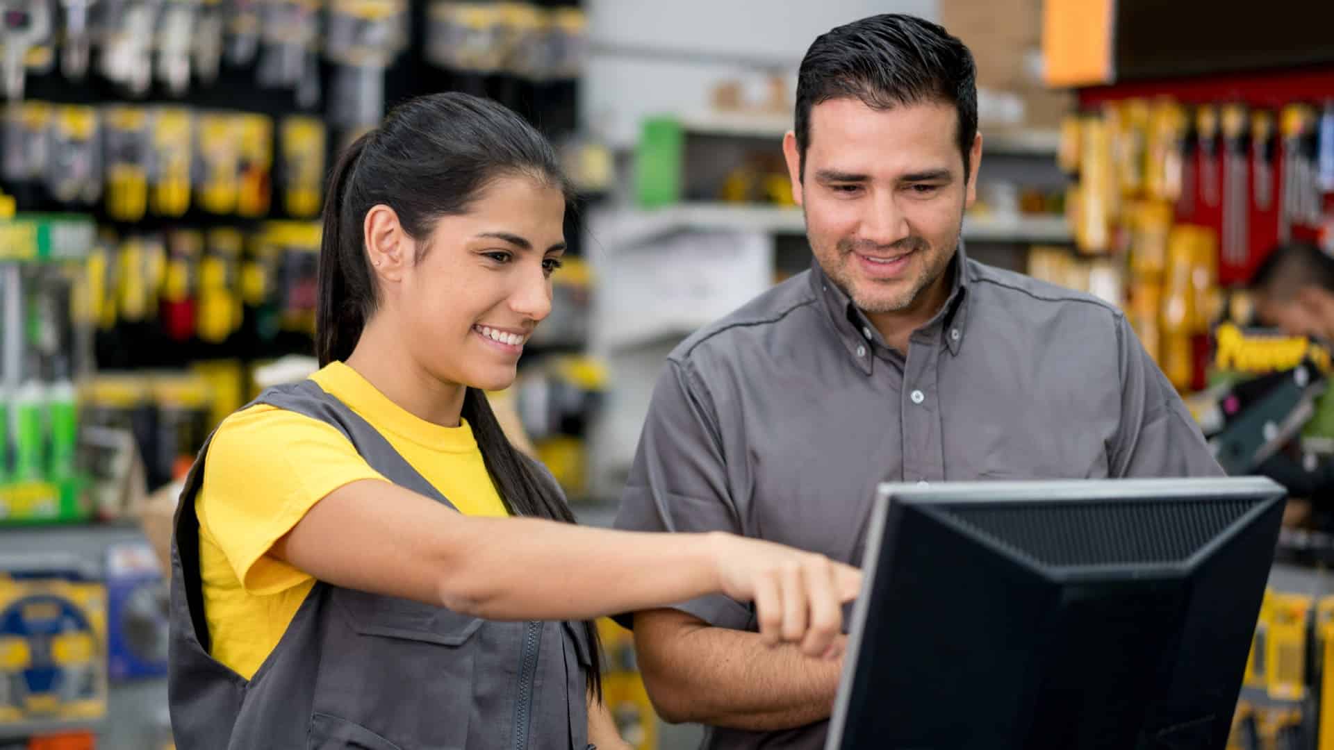 A man and a woman looking at a computer monitor, as if analyzing data from employee monitoring software.