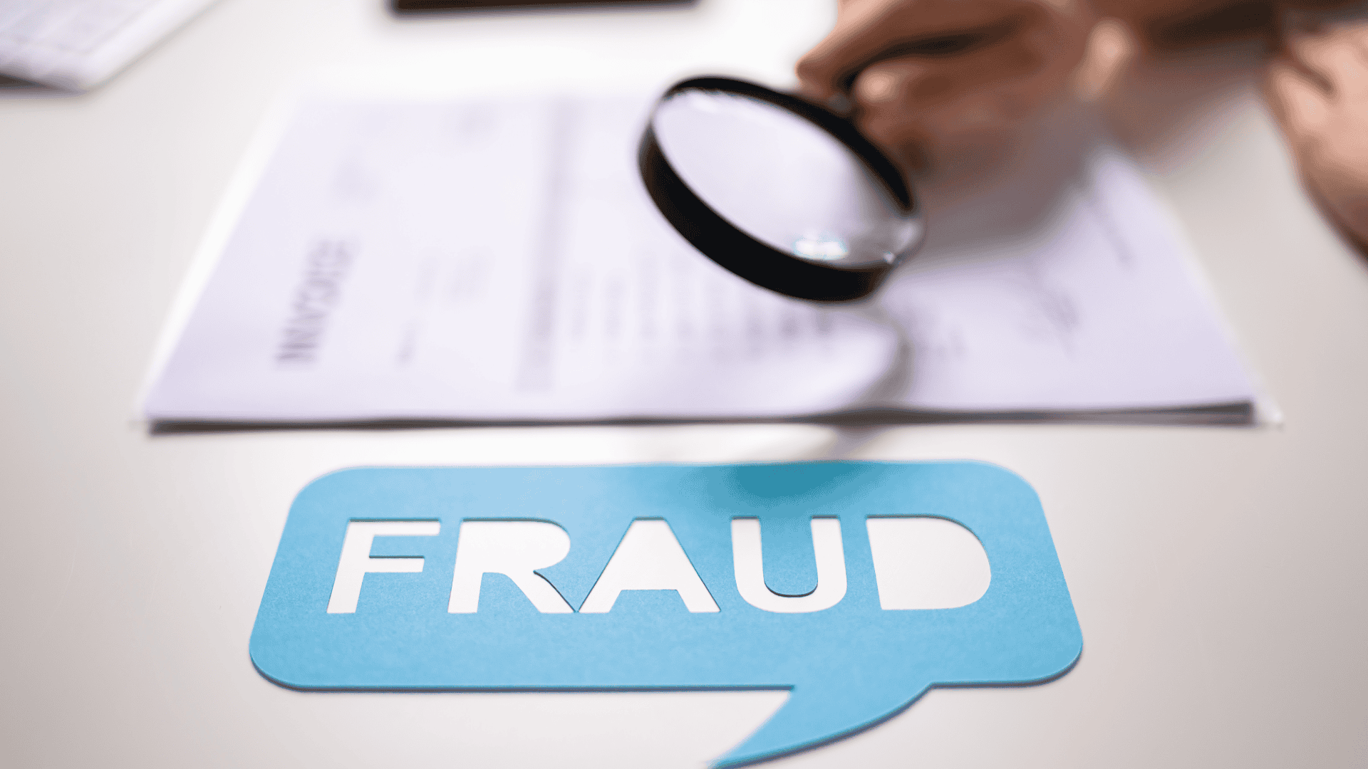 Image of a magnifying glass over a piece of paper labeled "Invoice." Next to it, a small blue sign with the word "Fraud" written on it. Like a fraud detection analysis.