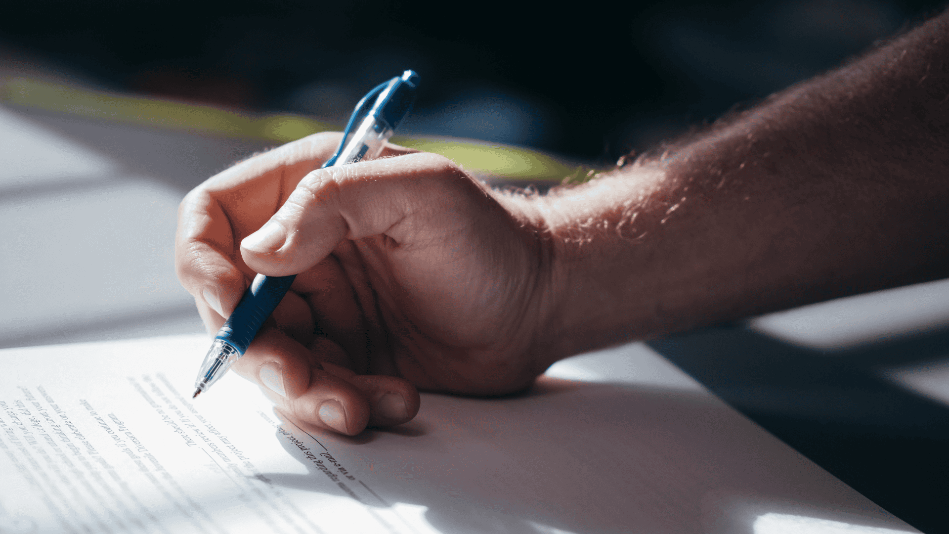 Close-up of a hand signing a document exemplifying compliance monitoring verification.