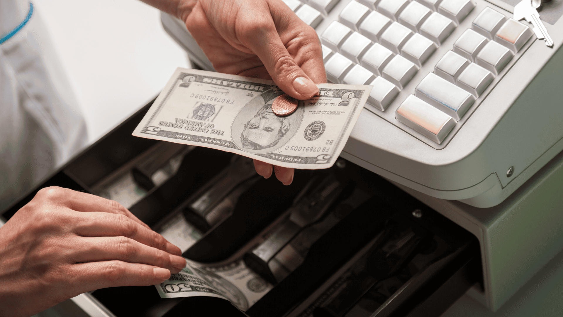 A close-up image of a man taking money from the cashier is an example of cash handling.