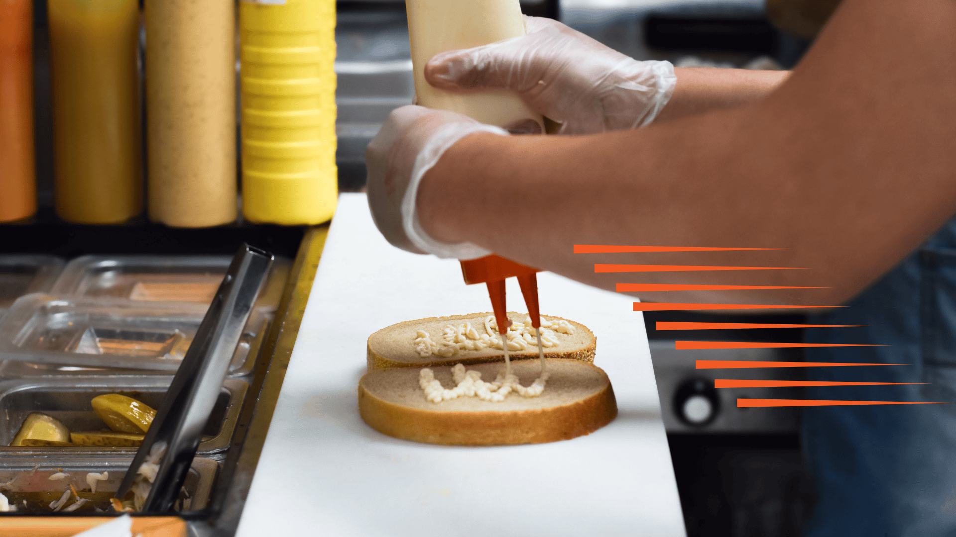 Close-up of a person putting dressing on a couple of pieces of bread as an example of QSR speed of service.