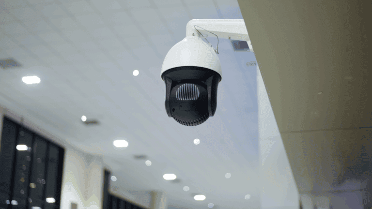 A ceiling-mounted security camera is shown inside a brightly lit building, highlighting surveillance technology often used in NVR vs DVR cameras comparisons.