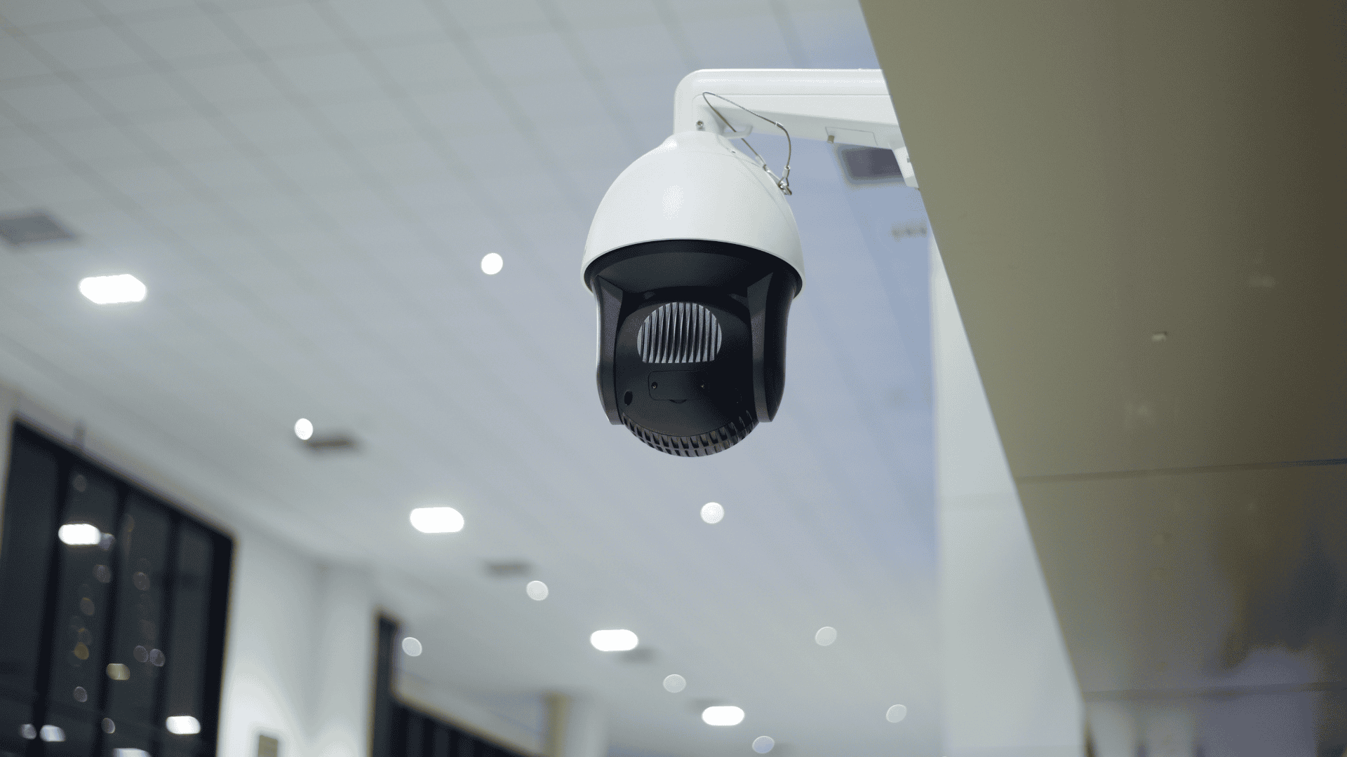 A ceiling-mounted security camera is shown inside a brightly lit building, highlighting surveillance technology often used in NVR vs DVR cameras comparisons.