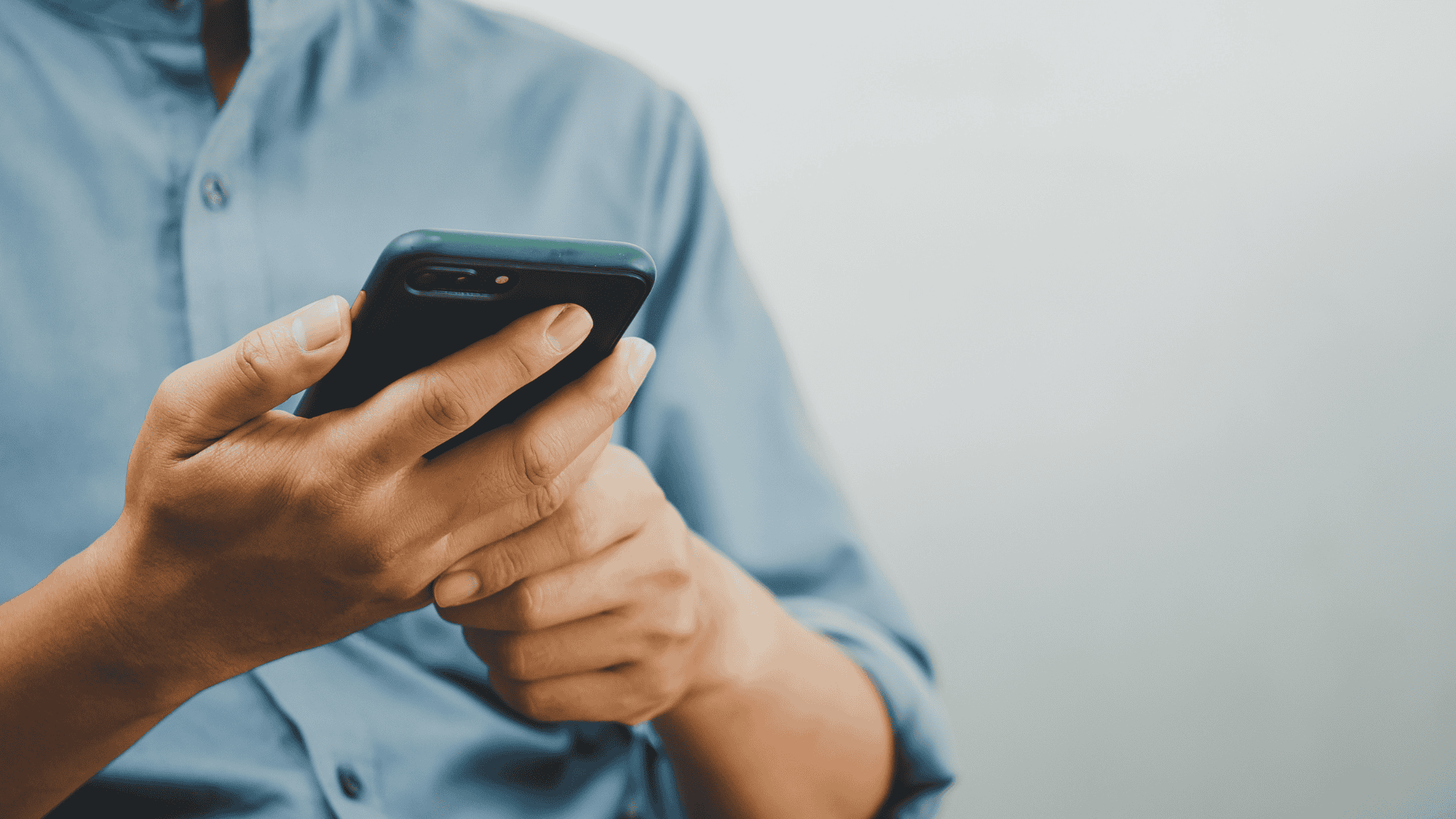 Close-up photograph of a man using his cell phone as an example of remote access to security and surveillance systems.