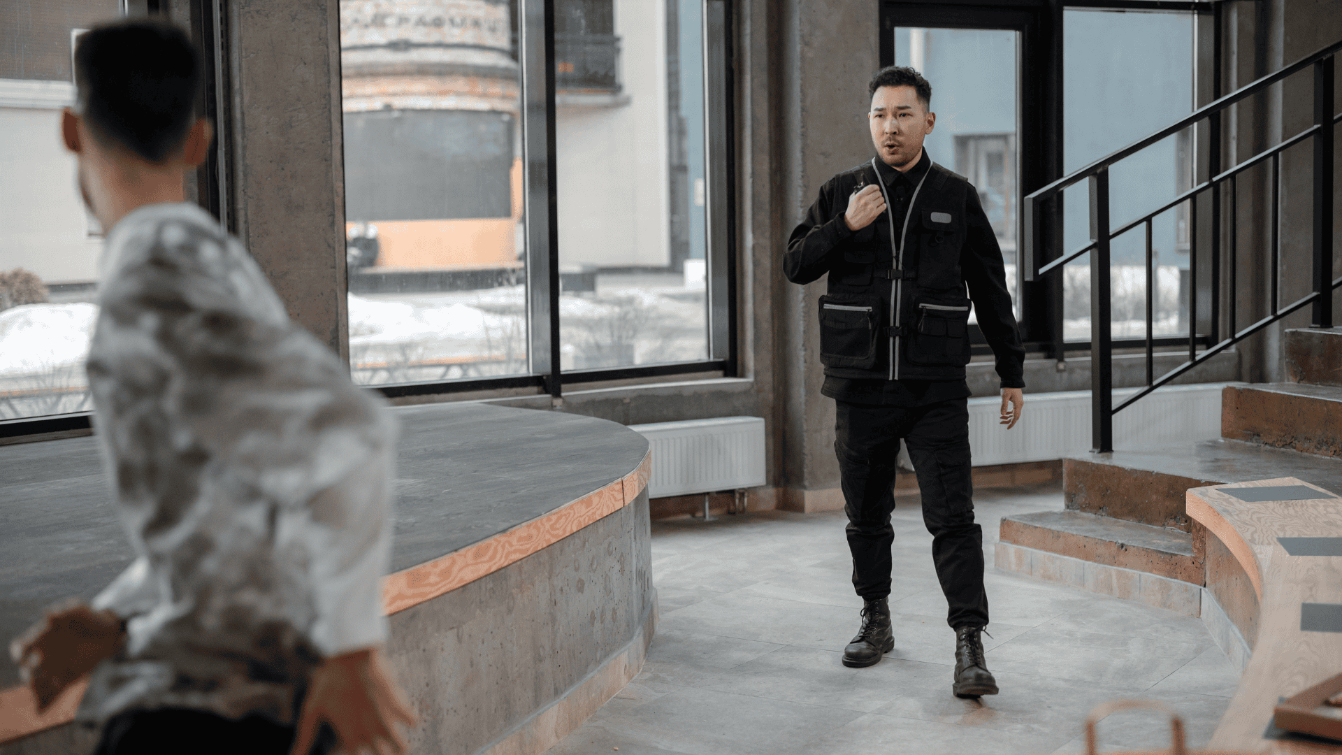 A security guard confronts a man who appears to be fleeing inside a modern office space, illustrating one of the types of employee theft.
