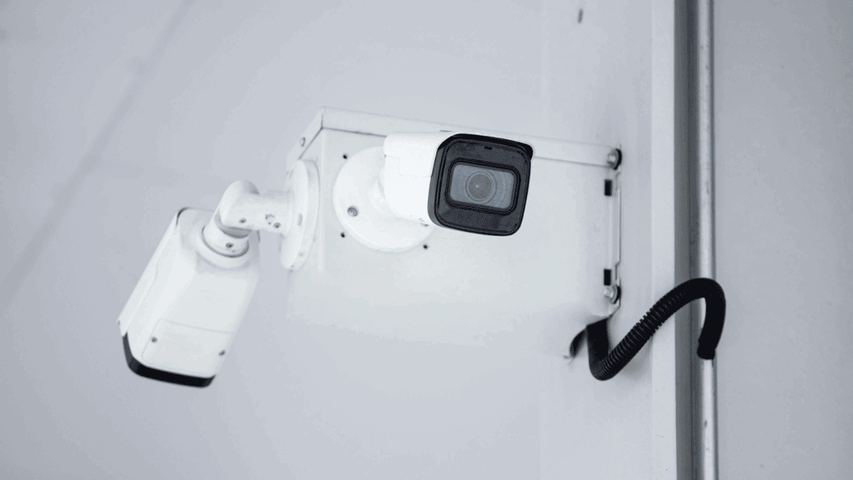 A close-up of a mounted white security camera with visible wiring, illustrating key features often compared in analog vs digital IP security cameras.