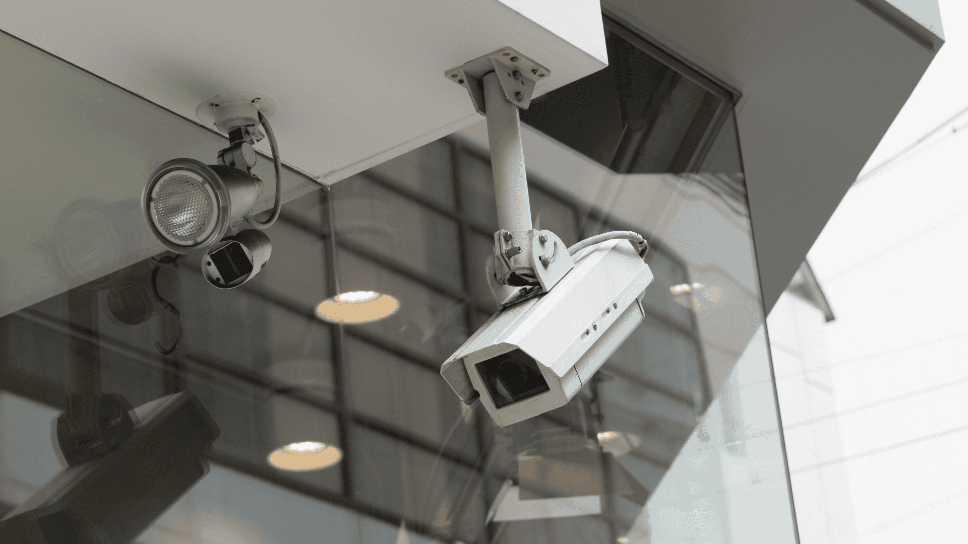Two different types of security cameras are mounted on the exterior of a modern building, visually representing a comparison in the topic Turret vs Dome security camera.
