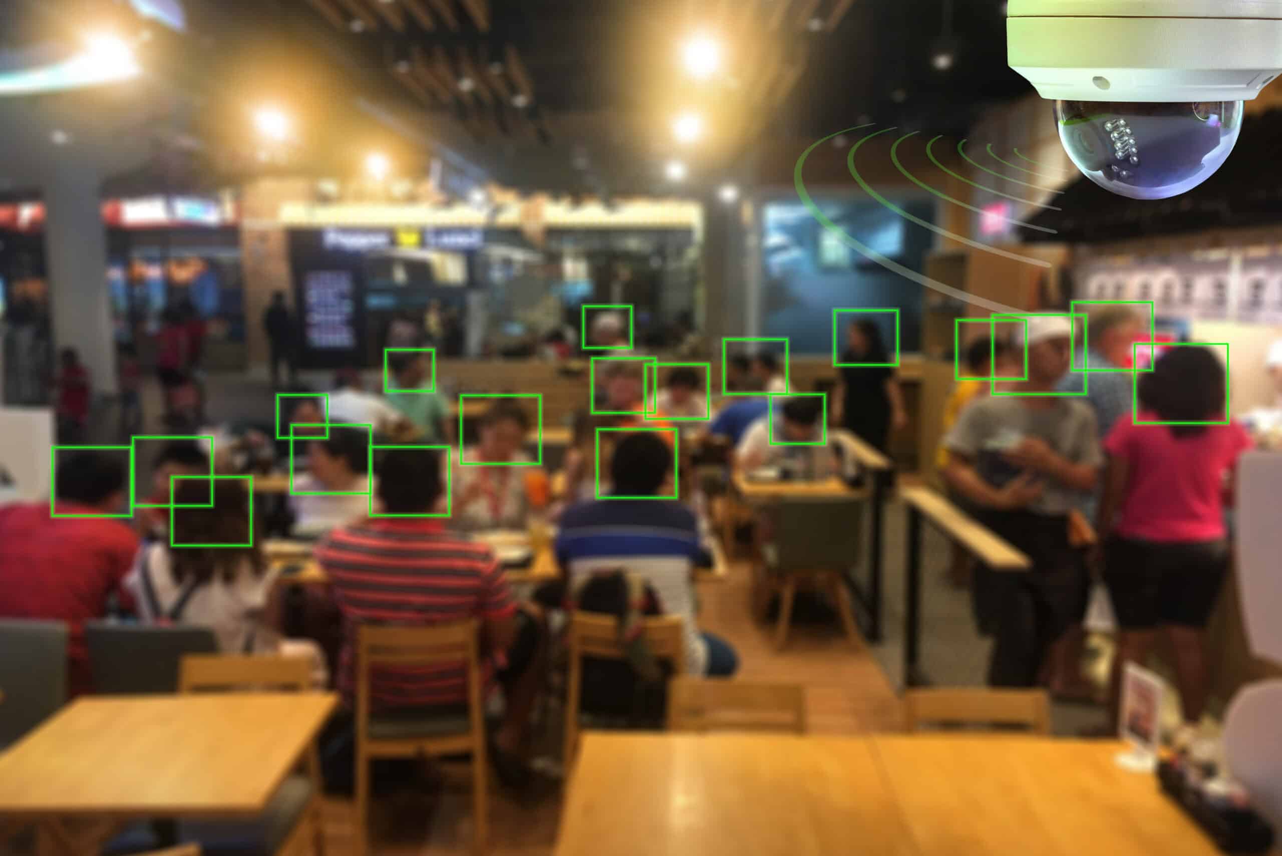 Security camera view of a food court with people detected in green boxes