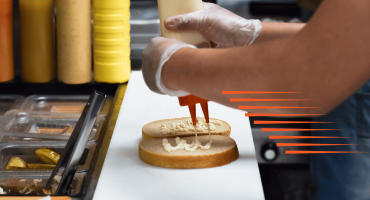 Close-up of a person putting dressing on a couple of pieces of bread as an example of QSR speed of service.
