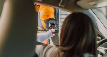 Image of a woman paying with her credit card from her car. Useful for analyzing how to improve drive thru speed of service.