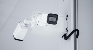 A close-up of a mounted white security camera with visible wiring, illustrating key features often compared in analog vs digital IP security cameras.