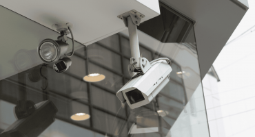 Two different types of security cameras are mounted on the exterior of a modern building, visually representing a comparison in the topic Turret vs Dome security camera.